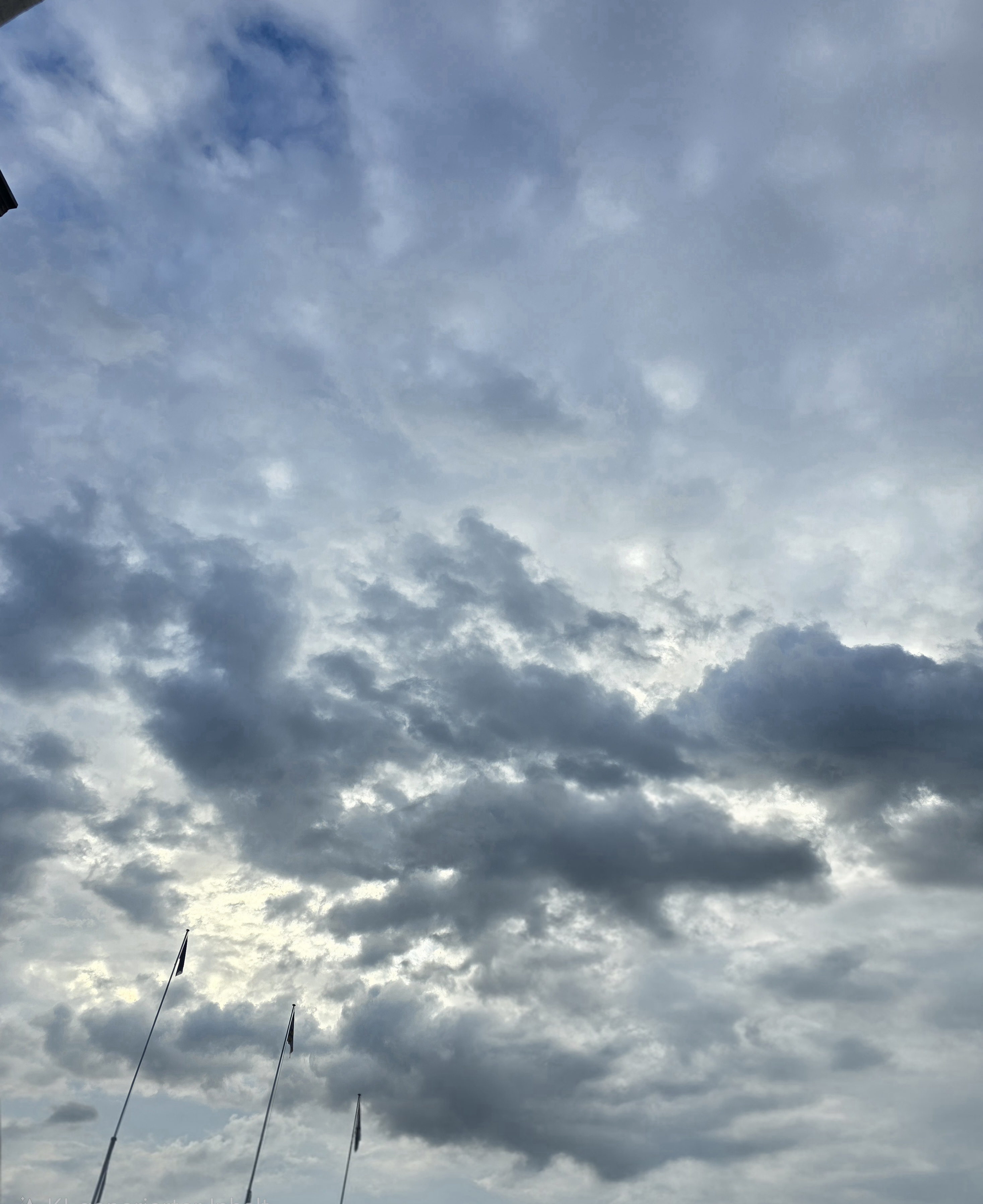 Dunkle, ballige Wolken vor einem helleren Wolkenhintergrund, mit kleinen blauen Lücken über Davos Dorf
