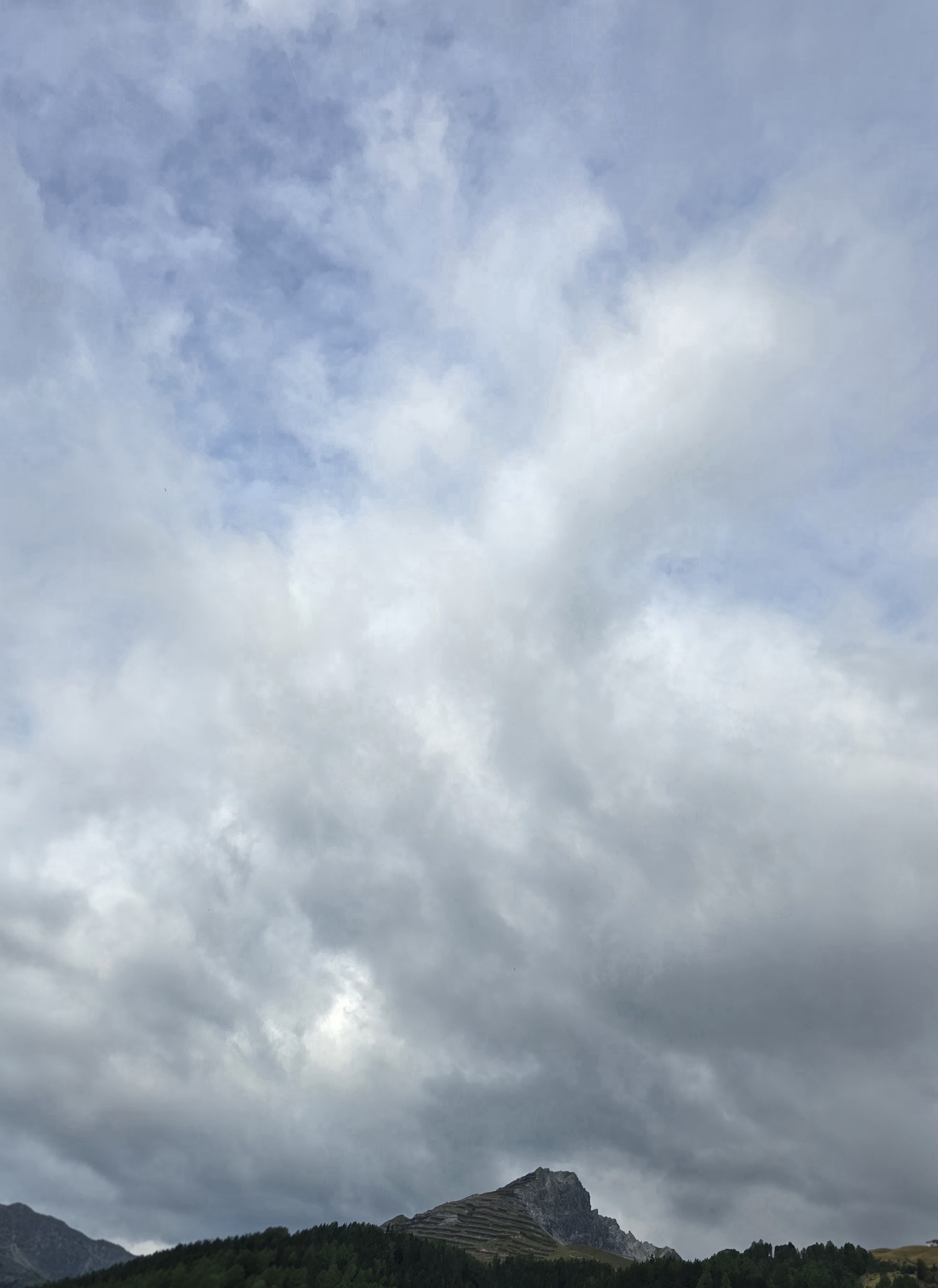 Eine dichtere grauweisse Wolkendecke prägt den Blick nach oben. Nur noch wenige kleine Stellen lassen Blau durchscheinen.