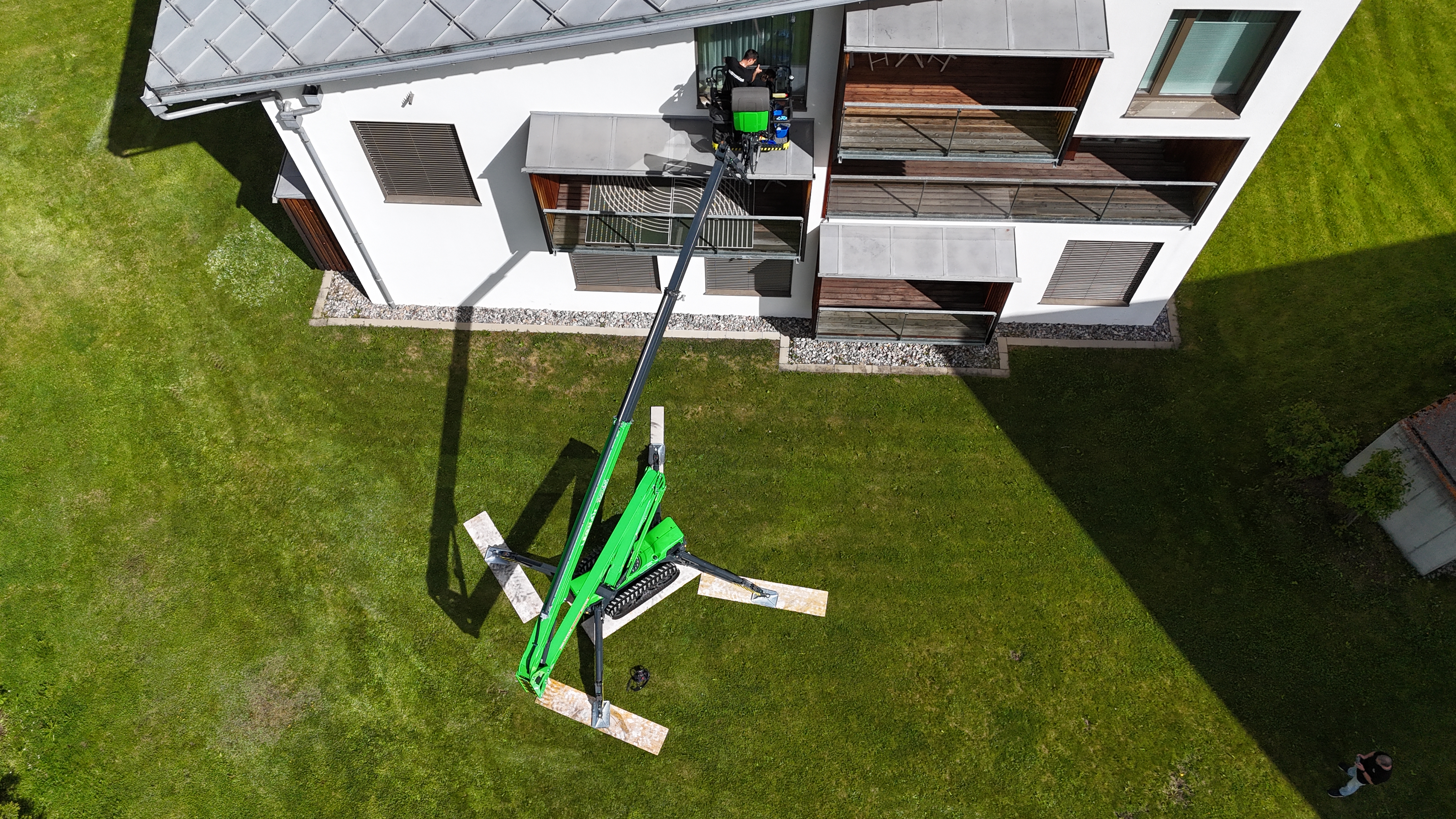 Grüne Arbeitsbühne vor einem Haus, von oben aufgenommen