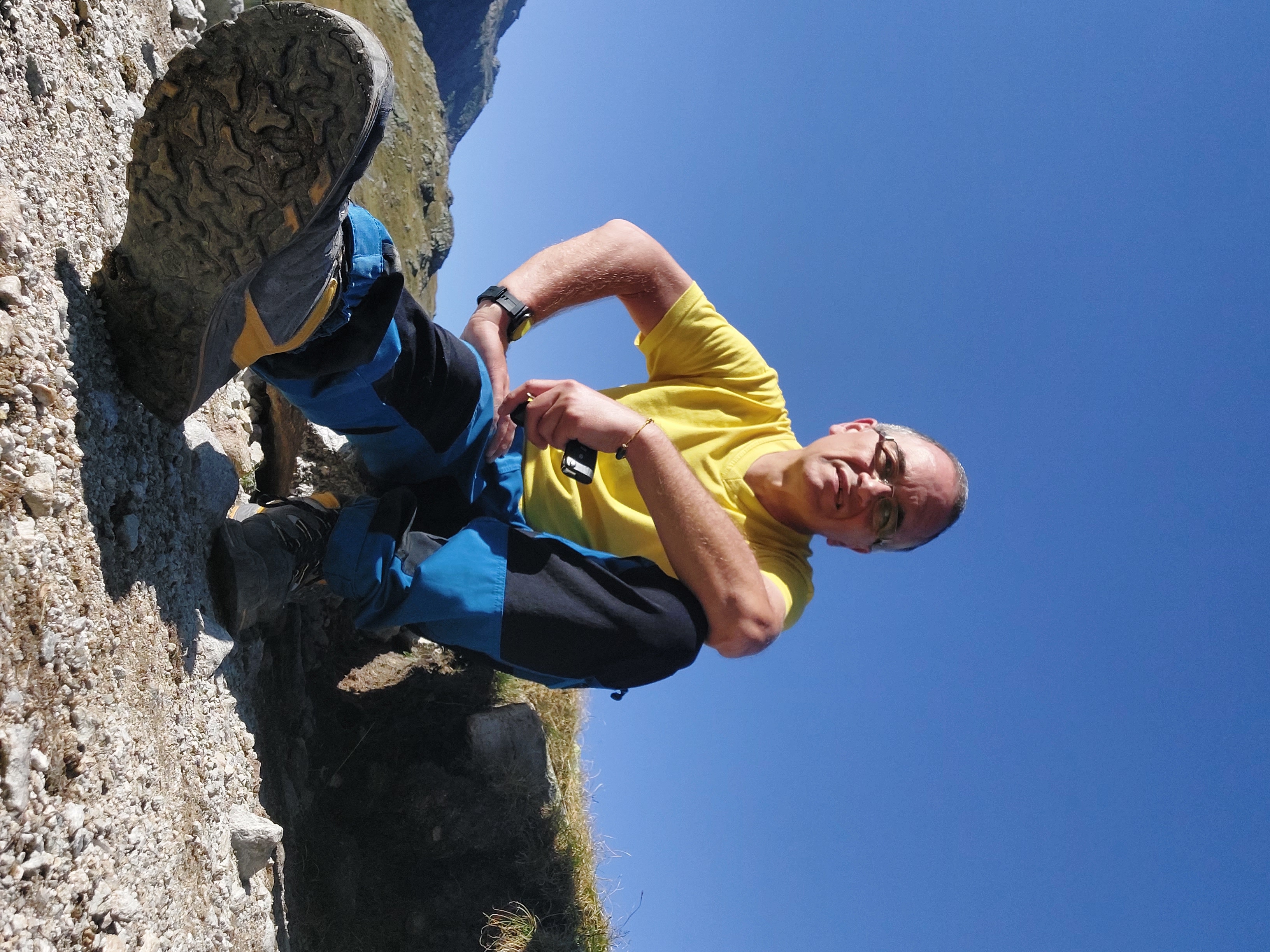 Jürgen im gelben T-Shirt bei einer Pause auf einem felsigen Bergweg