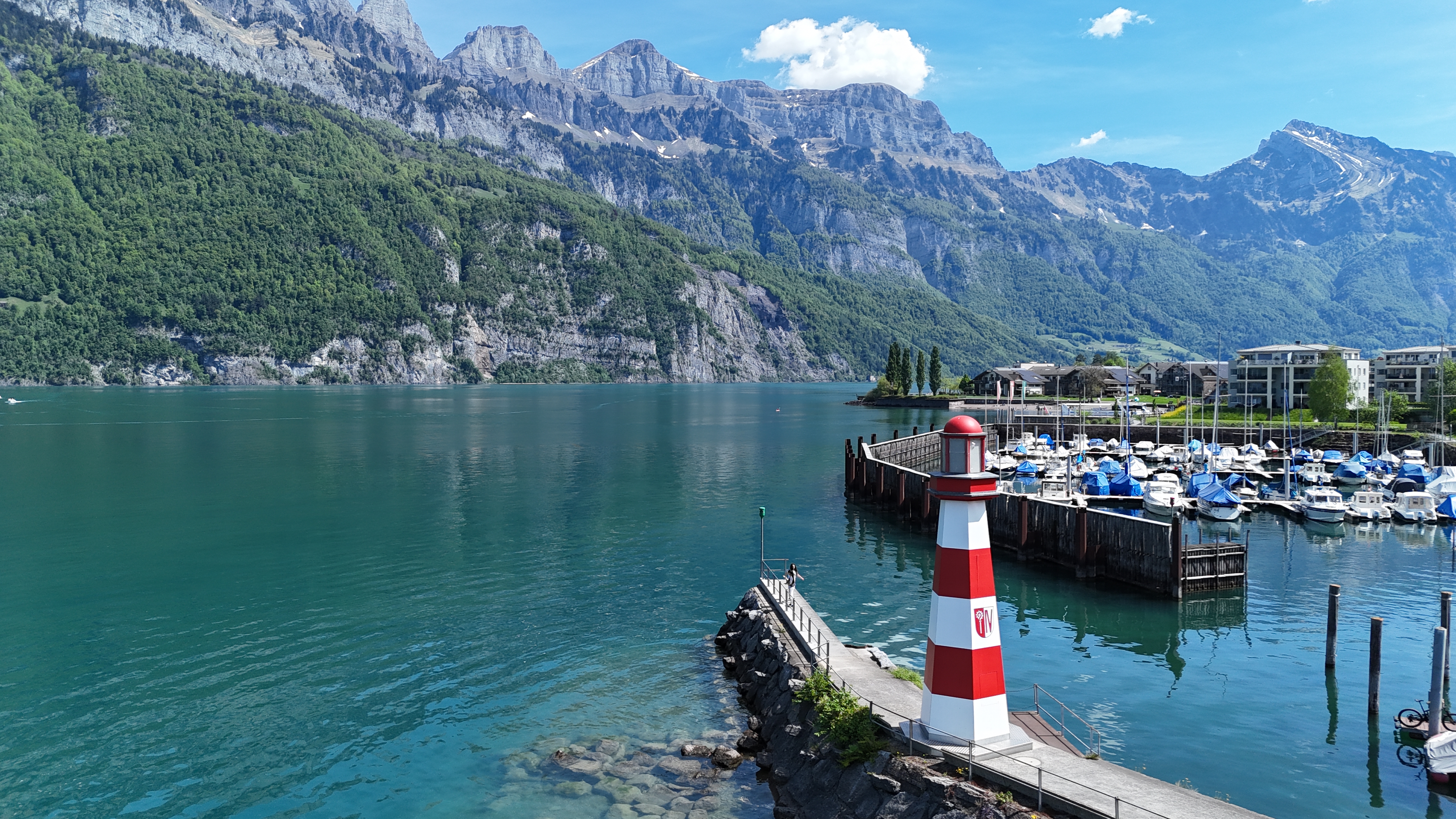 Walensee mit steilen Bergen, Hafen und rot-weissem Leuchtturm